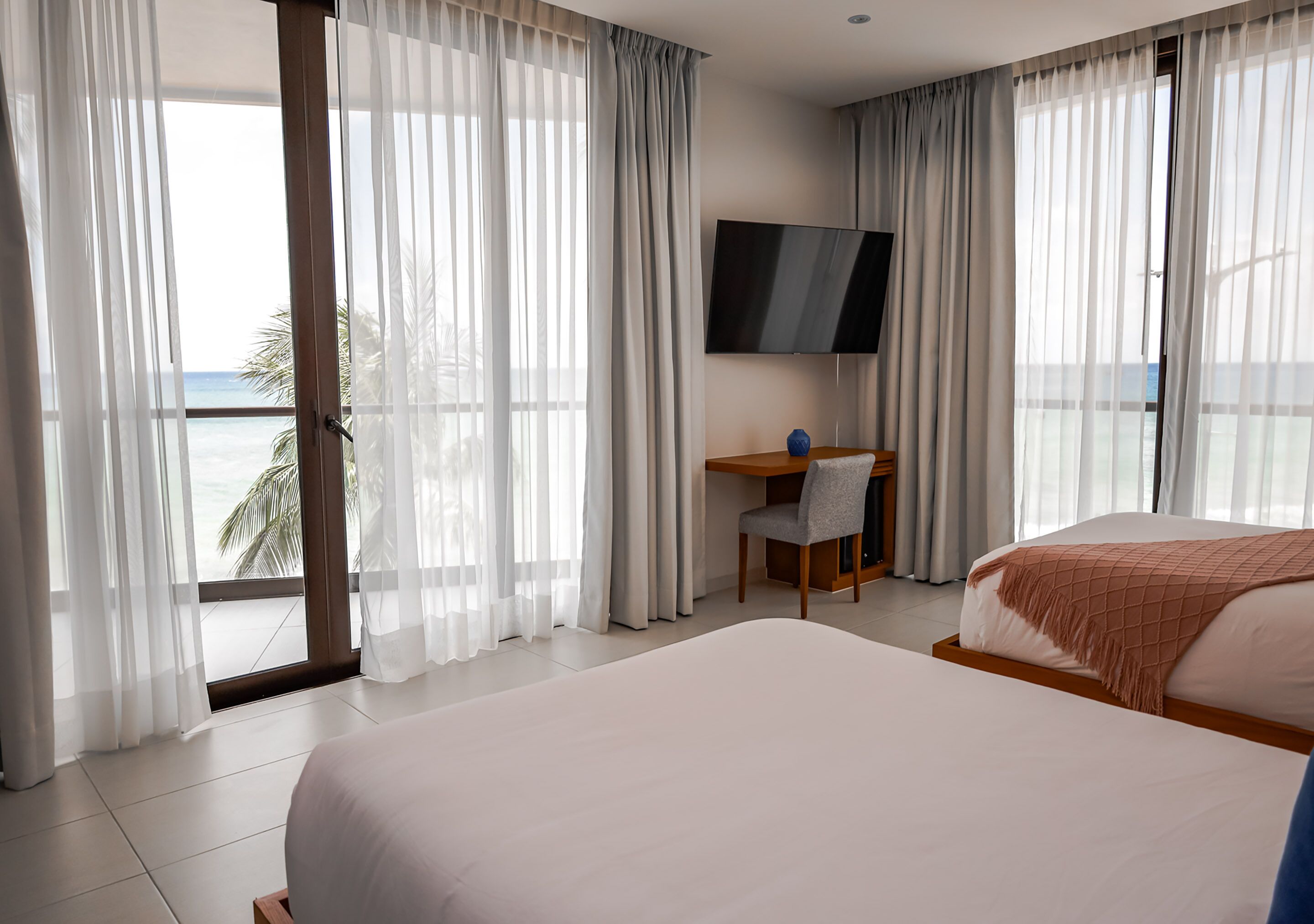 A hotel room with a bed, a desk, a chair, and a TV.