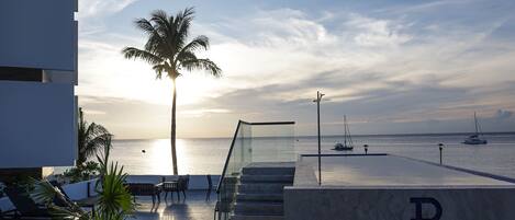 A modern hotel with a glass staircase leading to a terrace overlooking the sea.