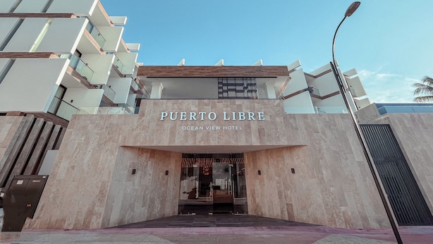 The exterior of Puerto Libre Ocean View Hotel with a clear sky.