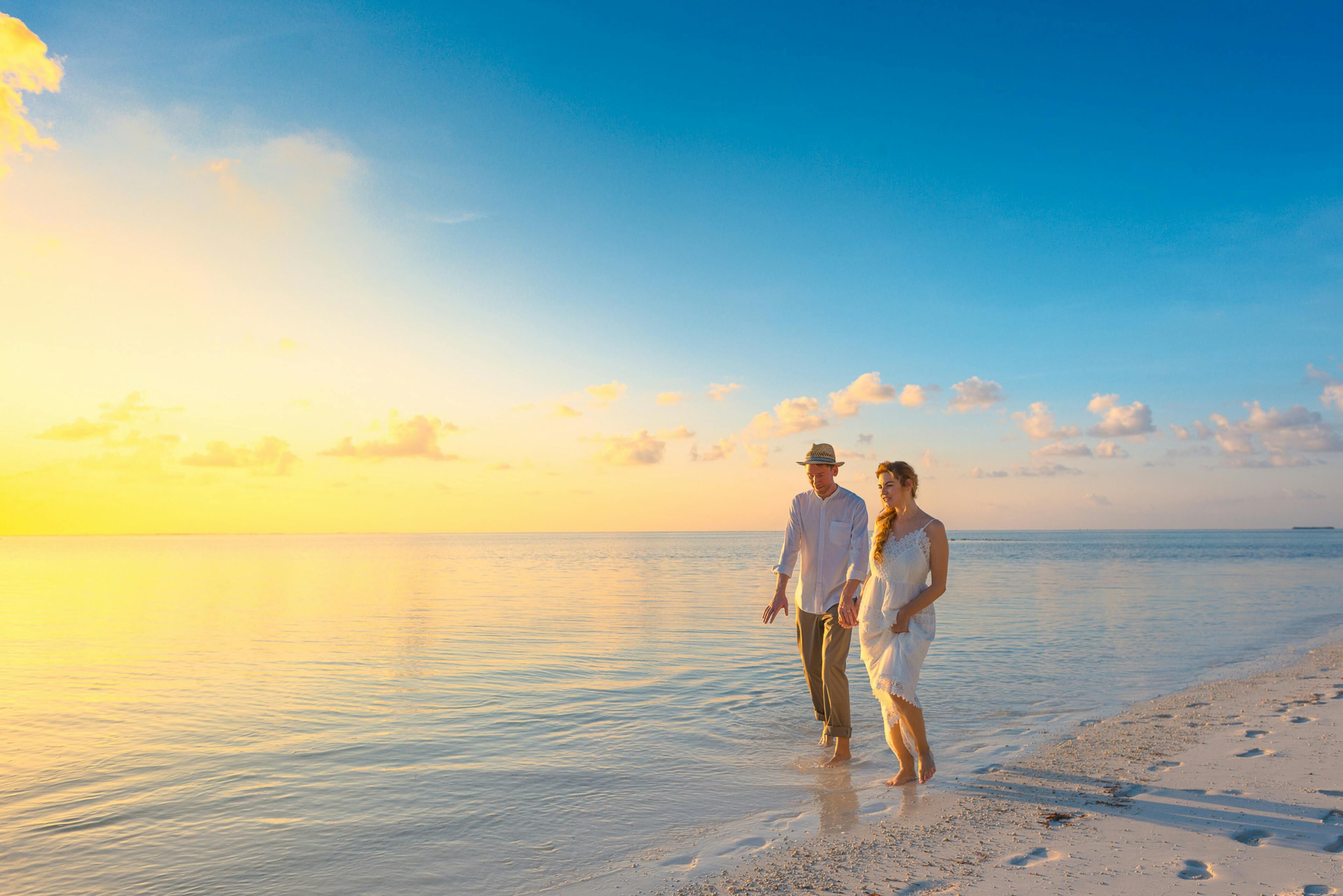 Una pareja caminando por la playa al atardecer.