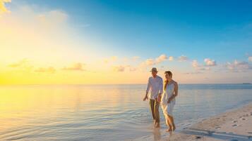 Una pareja caminando por la playa al atardecer.