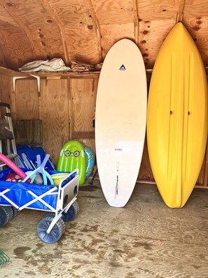 Un intérieur en bois avec deux planches de surf, une bleue et une jaune, et un chariot contenant divers objets.