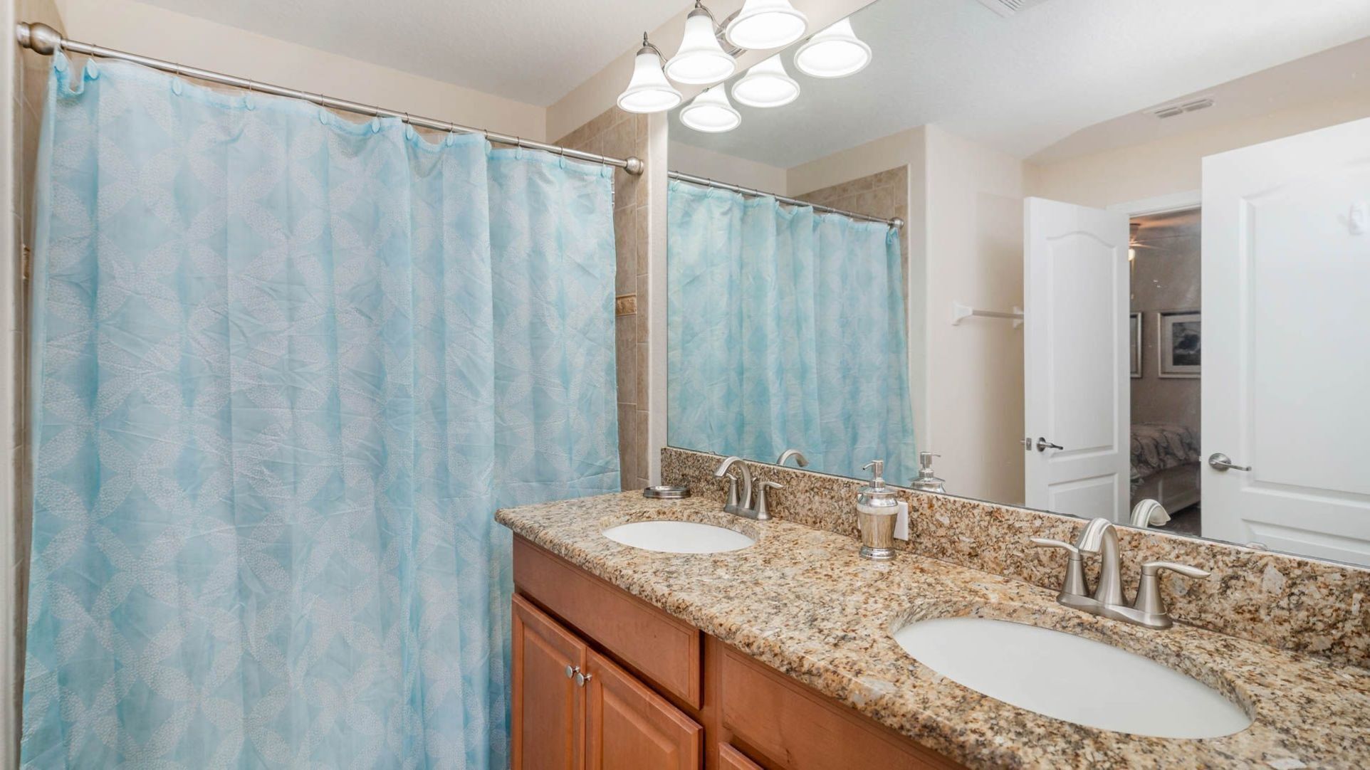 A bathroom with two sinks, a shower curtain, and a mirror.