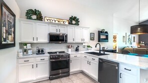 A modern kitchen with white cabinetry, stainless steel appliances, and a central island.