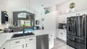 A modern kitchen with white cabinetry, a stainless steel refrigerator, and a dishwasher.