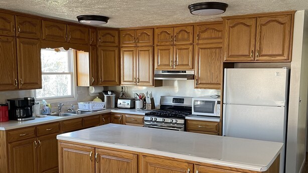 A kitchen with wooden cabinets, a stainless steel refrigerator, and a central island. - Pets, Families & Hunters Welcome  (Crofton)
