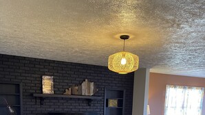 A living room with a black brick wall, a flat-screen TV, two patterned armchairs, a wooden coffee table, and a chevron-patterned rug. - Pets, Families & Hunters Welcome  (Crofton)