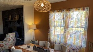 A dining area with a wooden table, four chairs, a hanging light fixture, and a patterned curtain. - Pets, Families & Hunters Welcome  (Crofton)