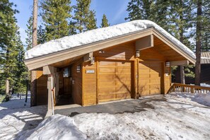 A wooden cabin with a snow-covered roof and a wooden door marked "162".