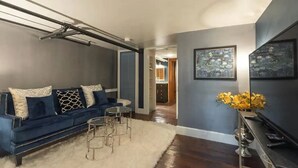 A living room with a blue sofa, a white rug, and a small round table. - The Biltmore Suite in historic Holladay House (Orange)