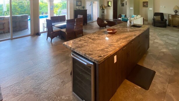 Una cocina amplia con una isla grande, vigas de madera y vistas a un patio exterior.