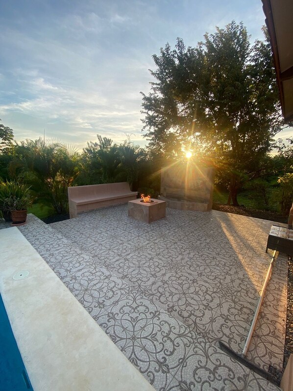 A patio with patterned flooring, a fire pit, and a seating area.