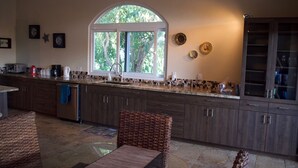 Una cocina moderna con armarios de madera oscura, un ventanal grande y una zona de comedor con sillas de mimbre.