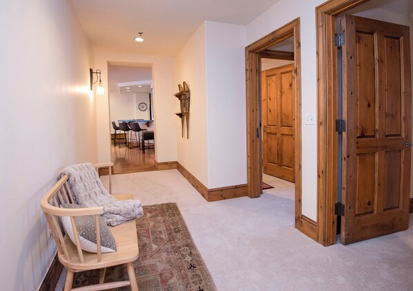 A hallway with a wooden bench, a rug, and a door leading to another room.