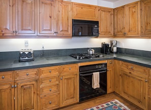 A kitchen with wooden cabinets, a black microwave, a stove, a dishwasher, and a coffee maker.