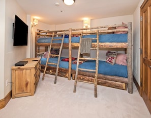 A bunk bed room with a wooden ladder, a TV mounted on the wall, and a small wooden cabinet. - Charlie Rentz: Ski-In/Out in Heart of Beaver Creek, Ice Rink Views, Walk Everywhere (Beaver Creek)