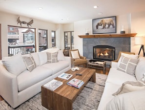 A cozy living room with a fireplace, a sofa set, and a coffee table with books and a remote control. - Charlie's Slopeside: Ski-In/Out in Heart of Beaver Creek, Ice Rink Views, Walk Everywhere (Beaver Creek)