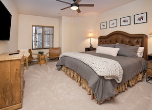 A bedroom with a large bed, a wooden dresser, a chair, a desk, a window, and wall-mounted animal pictures. - Charlie's Slopeside: Ski-In/Out in Heart of Beaver Creek, Ice Rink Views, Walk Everywhere (Beaver Creek)