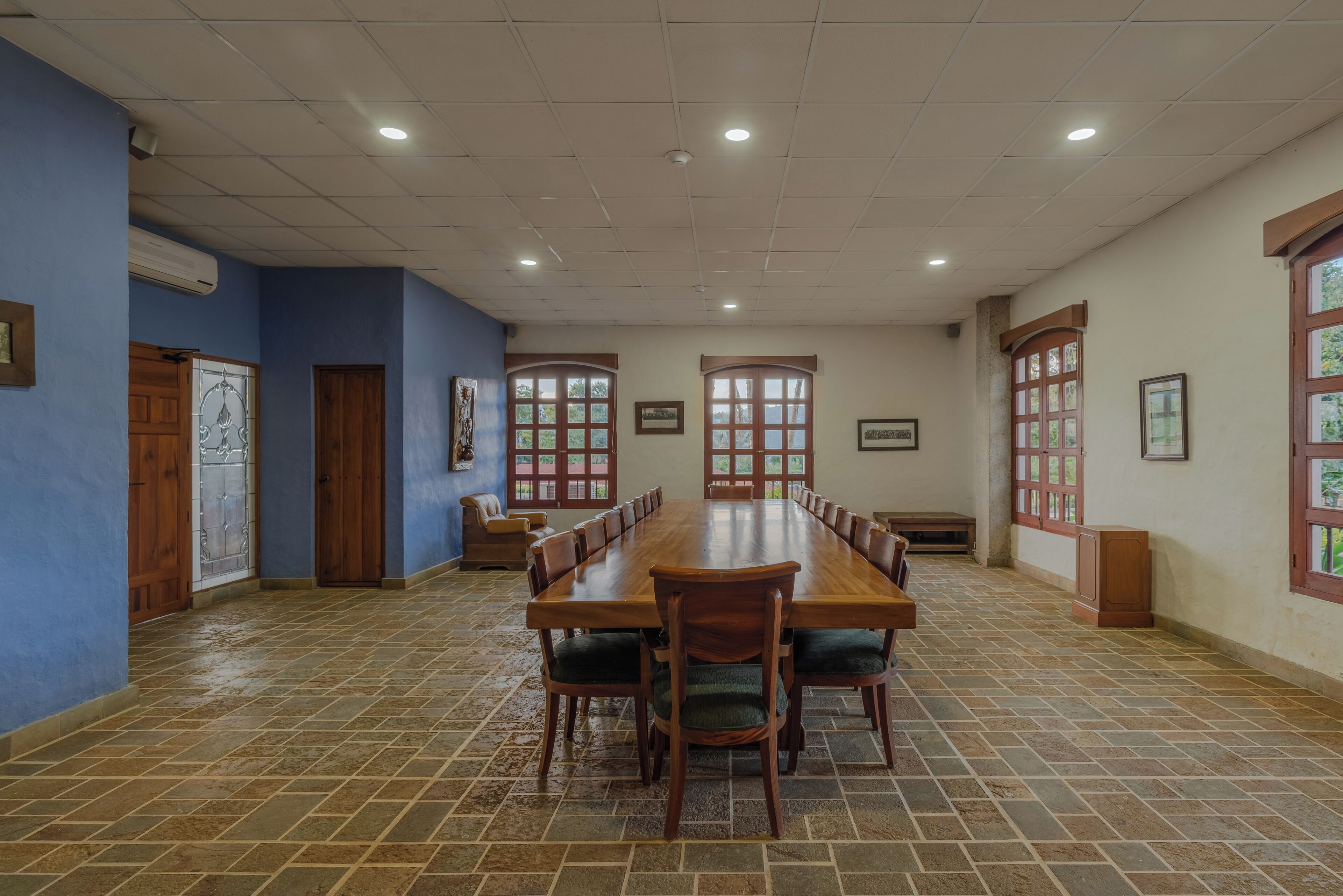 A conference room with a long wooden table, chairs, and a tiled floor.