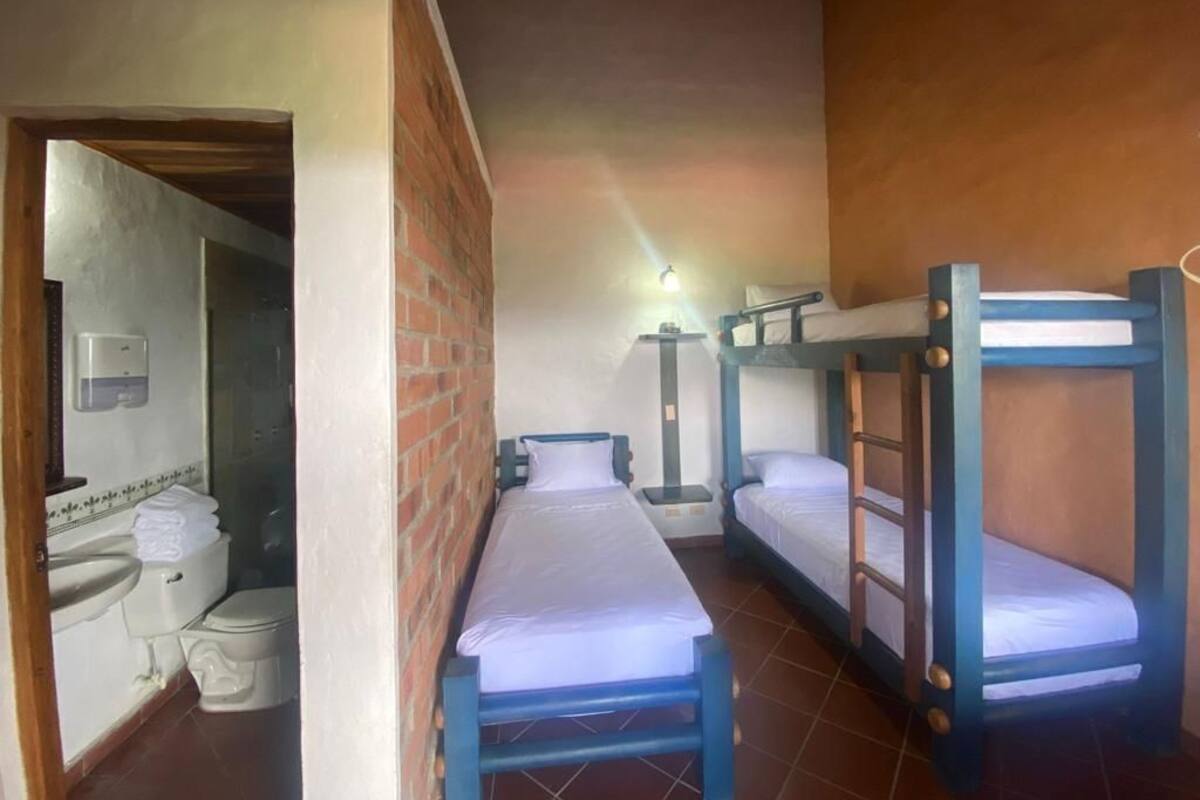 Quarto com beliches, pia e vaso sanitário.