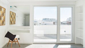 A modern, well-lit room with a large sliding glass door leading to an outdoor area. - ☀️ ❤️ Watch Sunsets over the Rooftops at an Old Town Penthouse (Albufeira)
