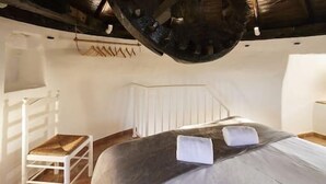 Ein Zimmer mit einem Bett, einem Sessel und einer Holzbalkendecke mit einer großen Radkonstruktion.