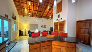 A kitchen with wooden cabinets, a granite countertop, and a dining area with red chairs.