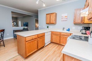 A modern kitchen with wooden cabinets, a white countertop, and a dishwasher.