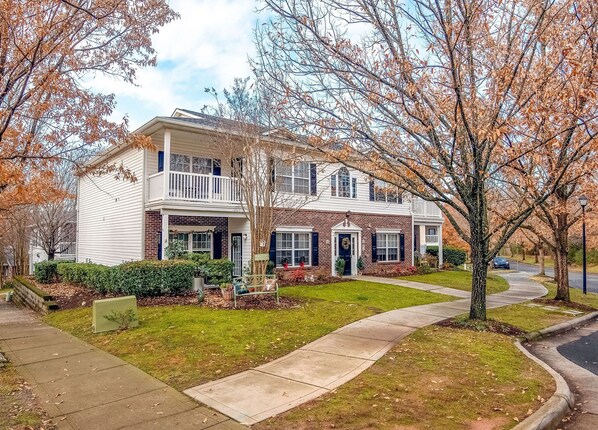 A two-story house with a front porch, a brick facade, and a well-maintained lawn. - *New* Charming 2BR Lake Norman Condo near Charlotte (Cornelius)