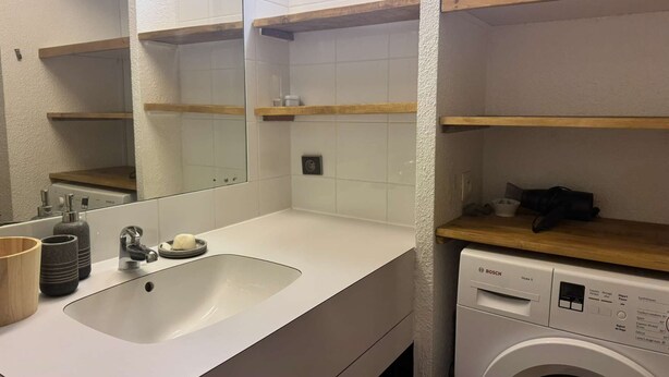 A bathroom with a sink, mirror, and a Bosch washing machine. - La Lauzière-Dessus 27 - Divisible studio on the edge of the slopes, with a terrace facing south (LES AVANCHERS VALMOREL)