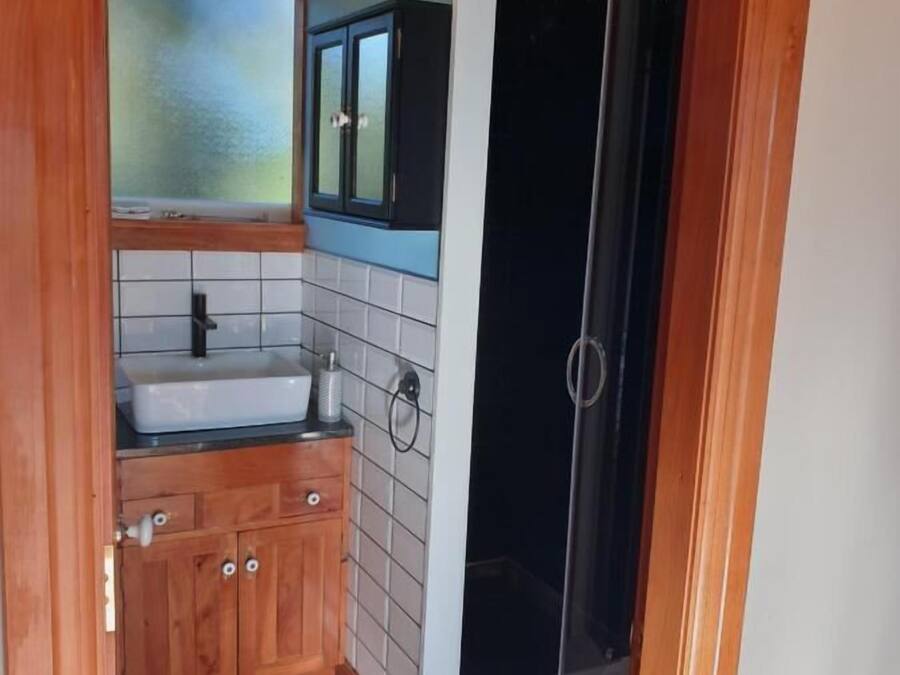 Een kleine keuken met een houten aanrecht, witte tegels, een spoelbak en kastjes.