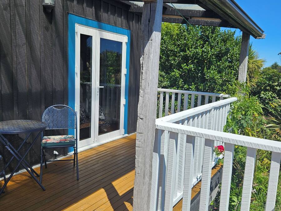 A wooden deck with a blue door, a white railing, and a blue watering can.