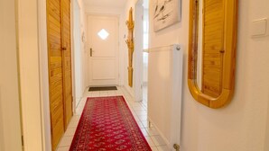 A hallway with wooden doors, a red patterned carpet, and a radiator on the wall.