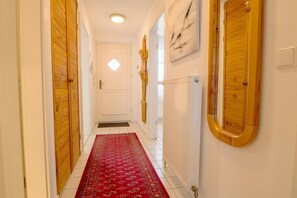Un pasillo con puertas de madera, una alfombra roja estampada y un radiador en la pared.