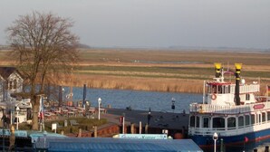 A waterfront area with a dock, a boat, and a building with outdoor seating.