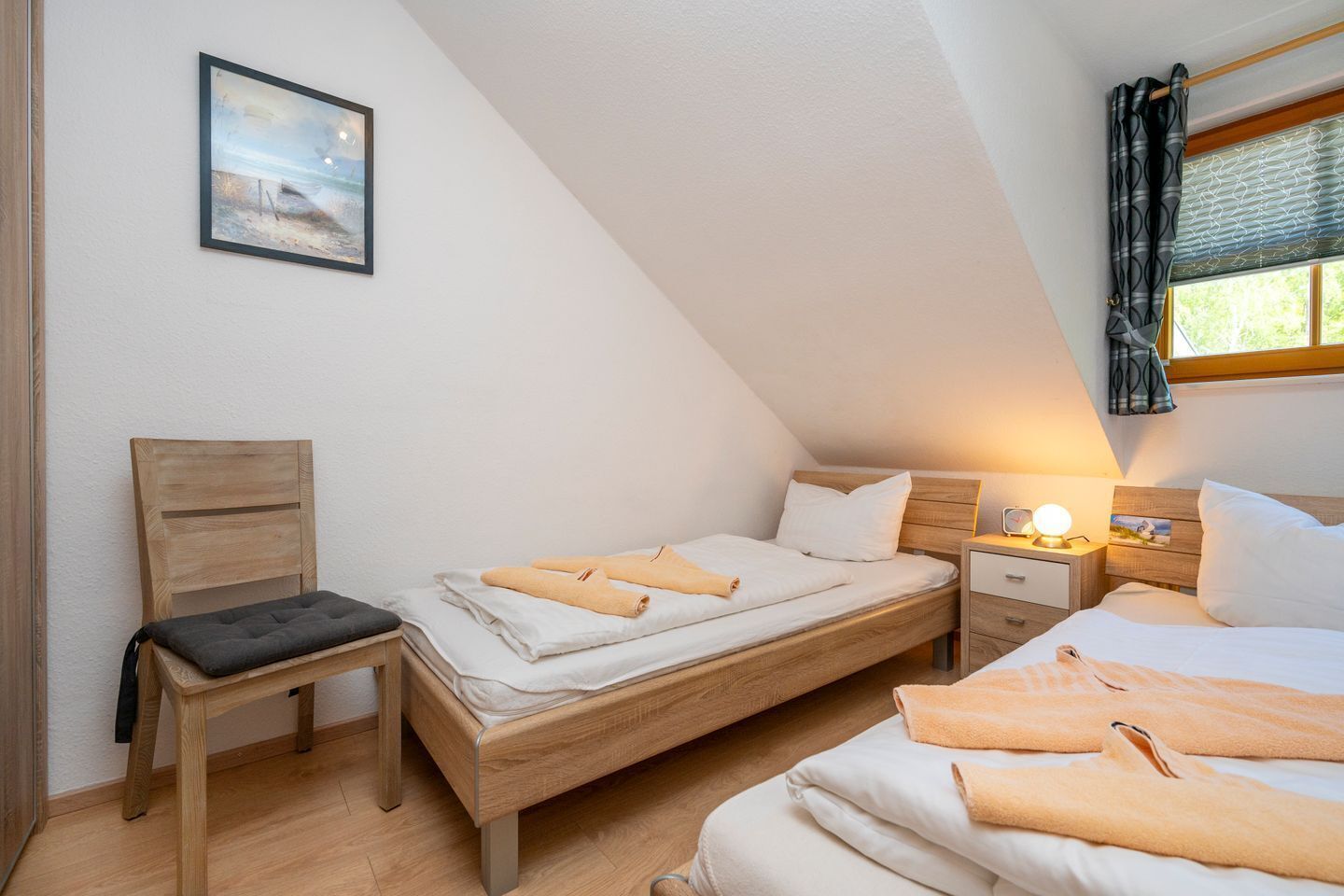 A cozy, well-lit room with a bed, a chair, and a bedside table.