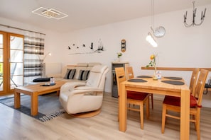 Ein modernes Wohnzimmer mit einer Couch, einem Esstisch mit Stühlen, einem Kamin und einer Wanduhr.