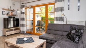 A modern living room with a grey sofa, wooden coffee table, and a TV on a wooden stand.