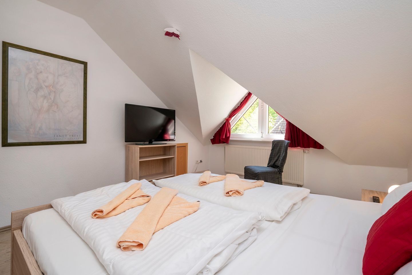 A bedroom with two beds, a television, a chair, and a window with red curtains.