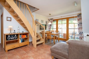 Ein gemütliches Wohnzimmer mit einer Holztreppe, einem Essbereich und einer Couch.
