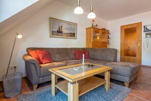 Ein gemütliches Wohnzimmer mit einer Couch, einem Glastisch, einem Gemälde, einem Holzschrank und einer Tür mit einem rauen Glasfeld.