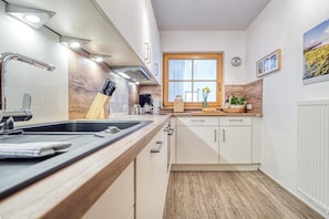 Een moderne keuken met een houten aanrecht, een roestvrijstalen spoelbak en een raam met uitzicht op de omgeving.