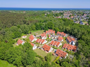 Vue aérienne d’un quartier résidentiel avec des maisons, des espaces verts et une côte.