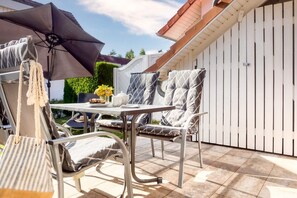 Une terrasse extérieure avec une table, des chaises et un parasol.