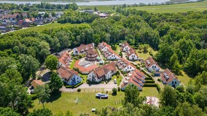 Ett flygbildsfoto av ett bostadsområde med hus, en sjö och en bro i bakgrunden.