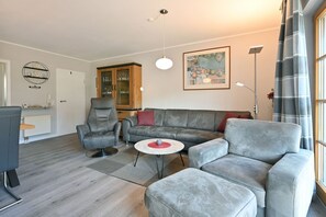 Un salon moderne avec des canapés gris, une table basse ronde et un meuble.
