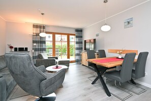 Un salon moderne avec des canapés gris, une table à manger en bois et un téléviseur.