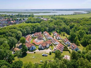 An aerial view of a residential area with houses, a lake, and a bridge in the background. - Comfortable vacation apartment in a vacation park with balcony and pool in Zingst - (Zingst)