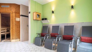 Un sauna avec des bancs en bois, une porte en bois et un radiateur fixé au mur.