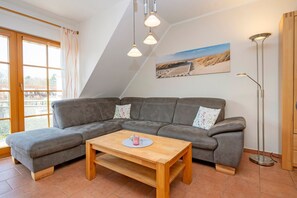 Ein modernes Wohnzimmer mit einem grauen Ecksofa, einem Holztisch und einer Stehlampe.